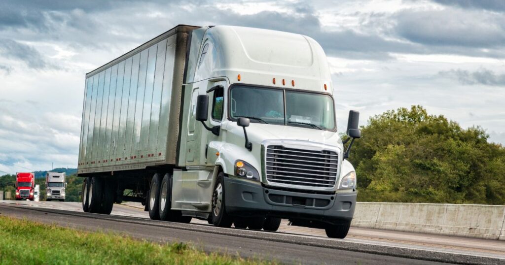 white tractor trailer driving on the road during day time